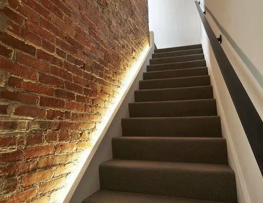 Escalier avec éclairage LED indirect sur mur de brique